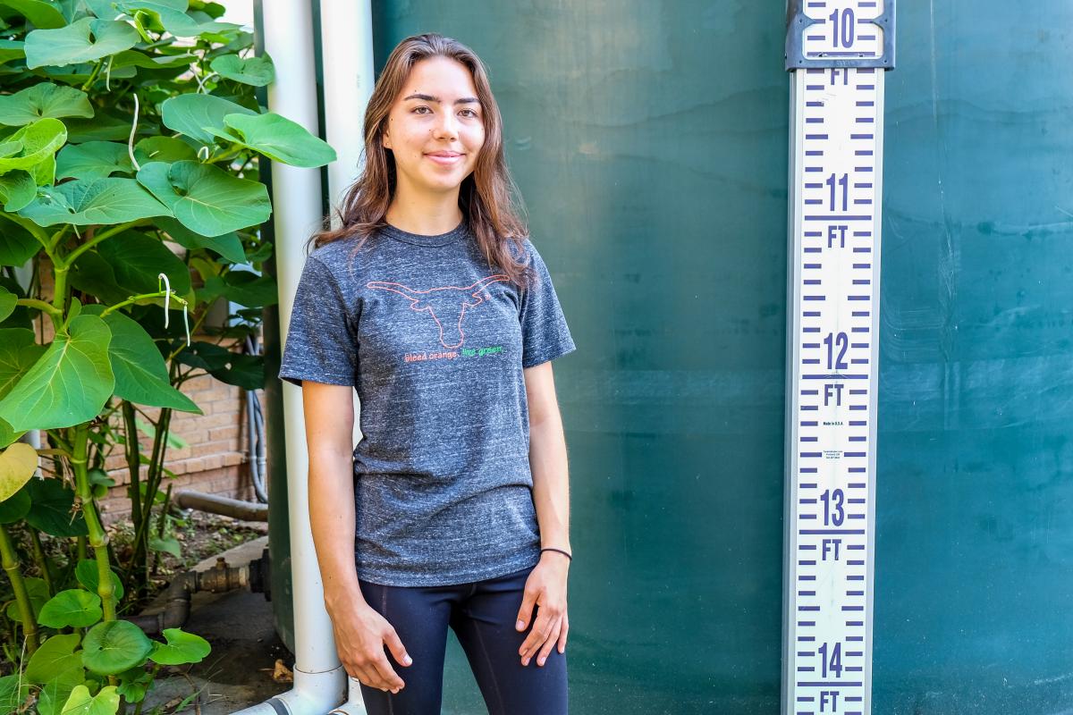 Susan standing near a plant and rain barrel.